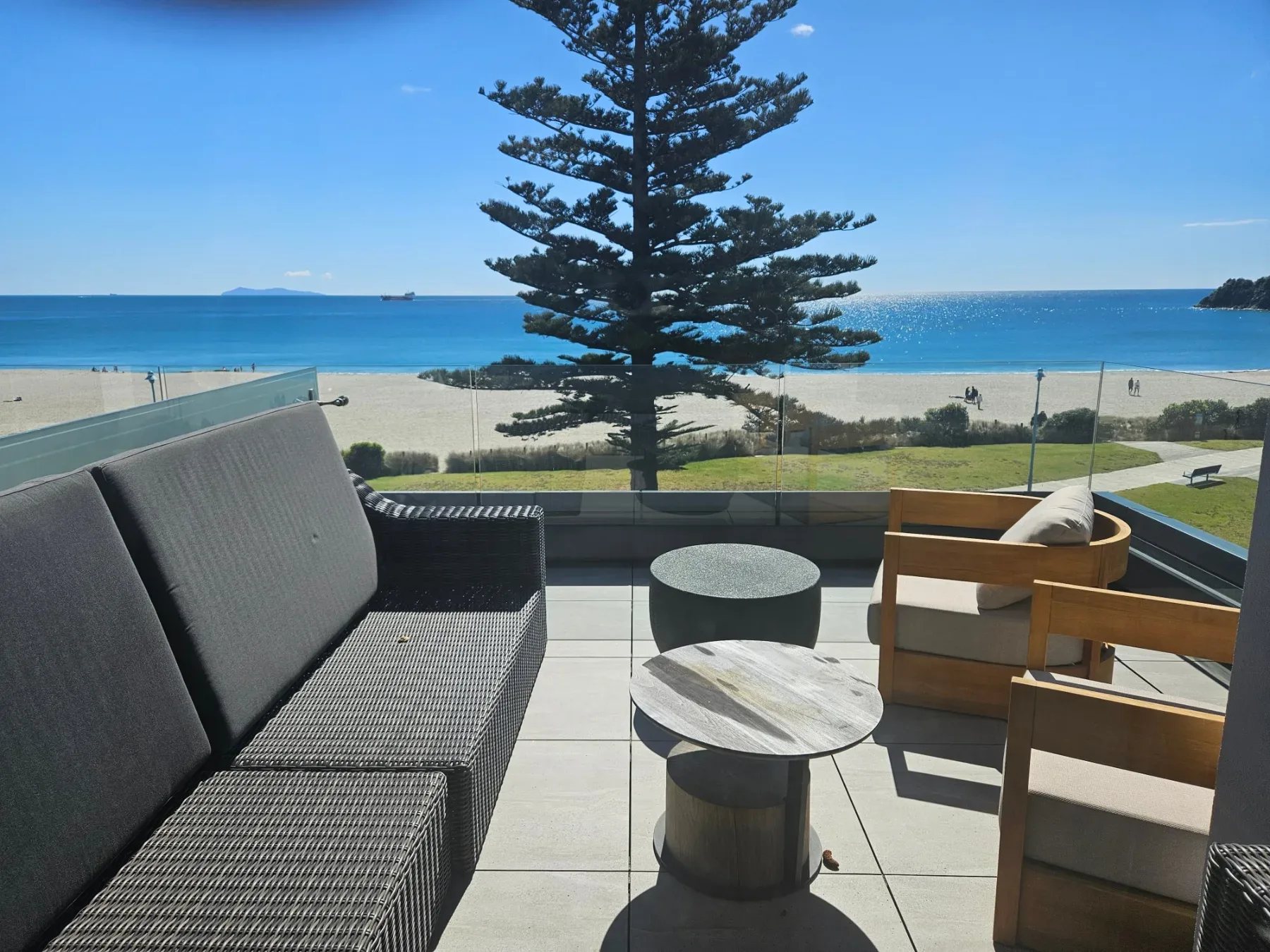 Balcony with outdoor seating overlooking Mount Maunganui Main Beach and the ocean.