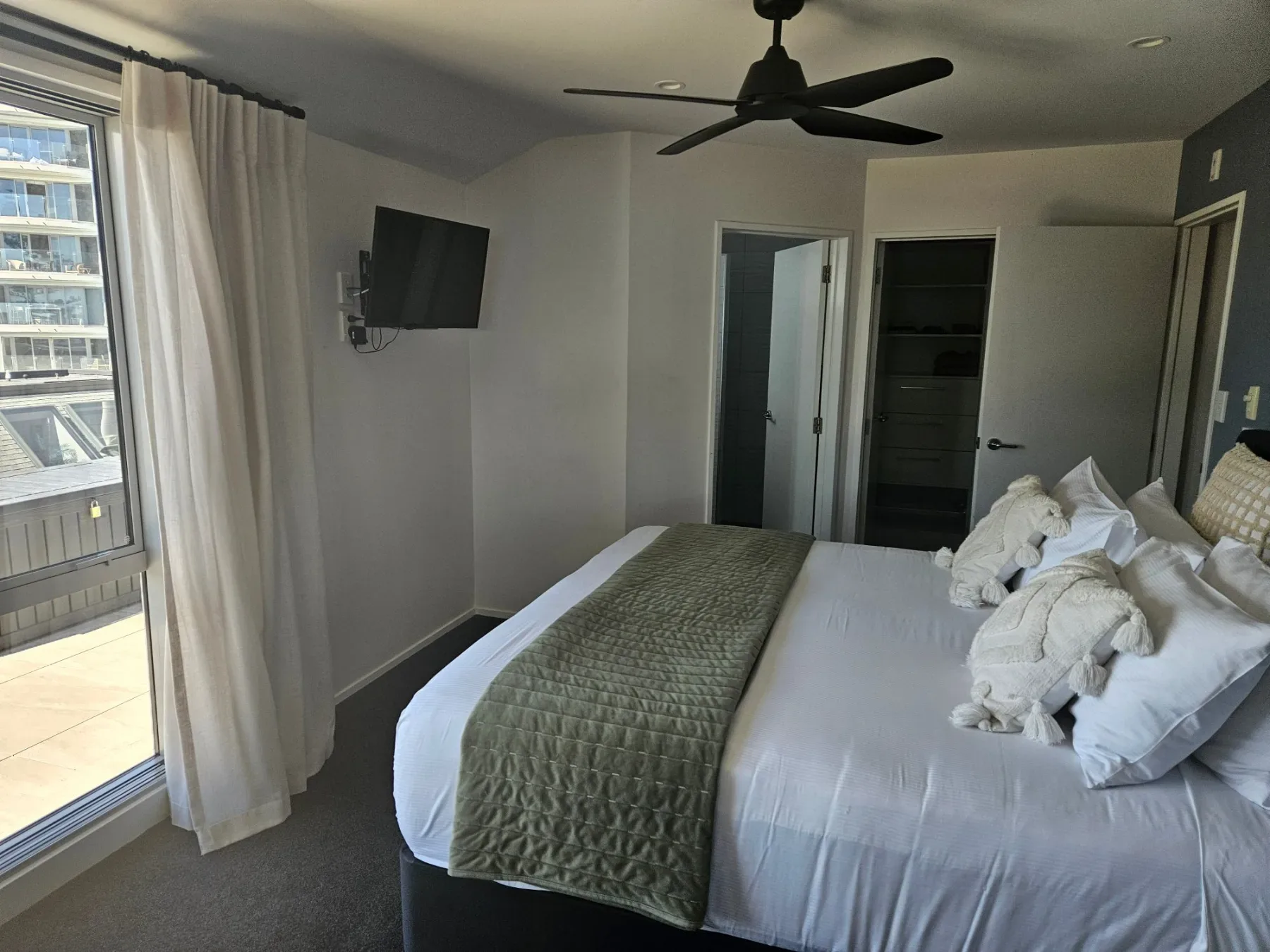 Bright bedroom with ceiling fan, wall-mounted TV and ensuite access.