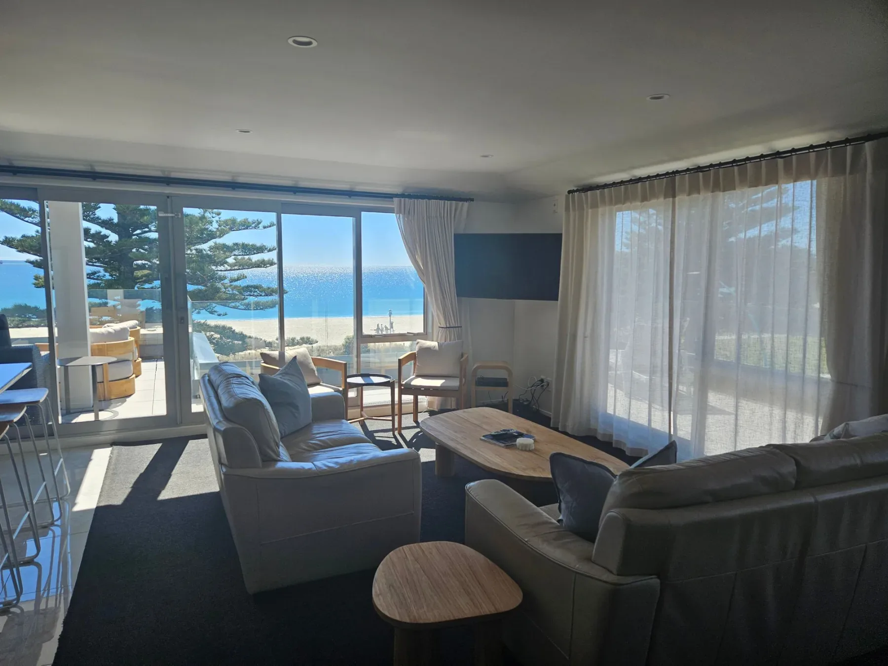 Lounge with leather sofas, coffee table and floor-to-ceiling windows overlooking Main Beach.